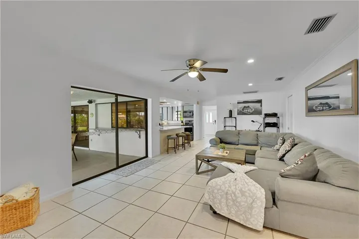 Living room featuring light tile patterned floors, ornamental molding, a ceiling fan, and recessed lighting