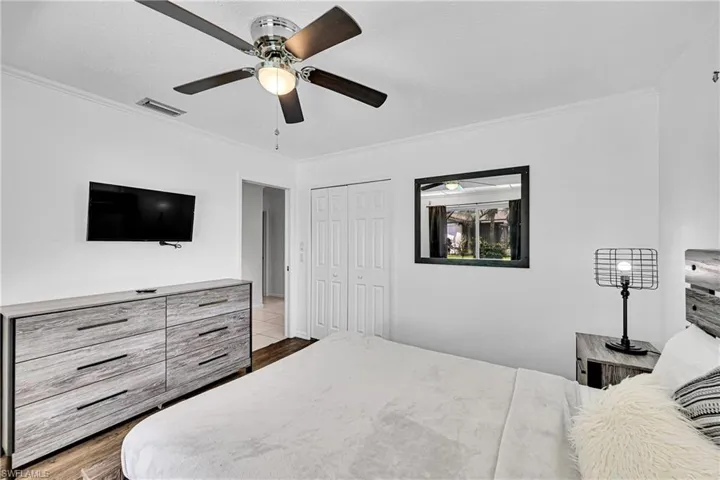 Bedroom featuring ornamental molding, a ceiling fan, dark wood-style floors, and a closet