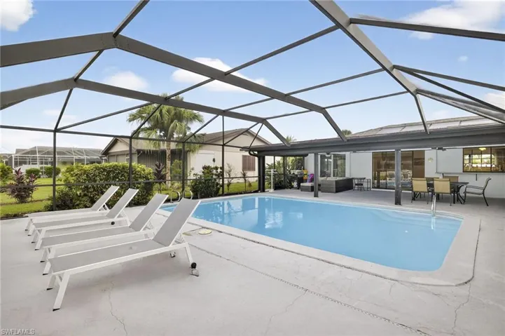 Outdoor pool featuring a sunroom, glass enclosure, a patio area, and an outdoor living space