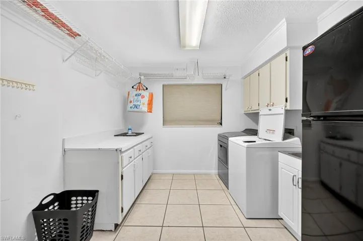 Laundry room featuring cabinet space, light tile patterned floors, a textured ceiling, and independent washer and dryer