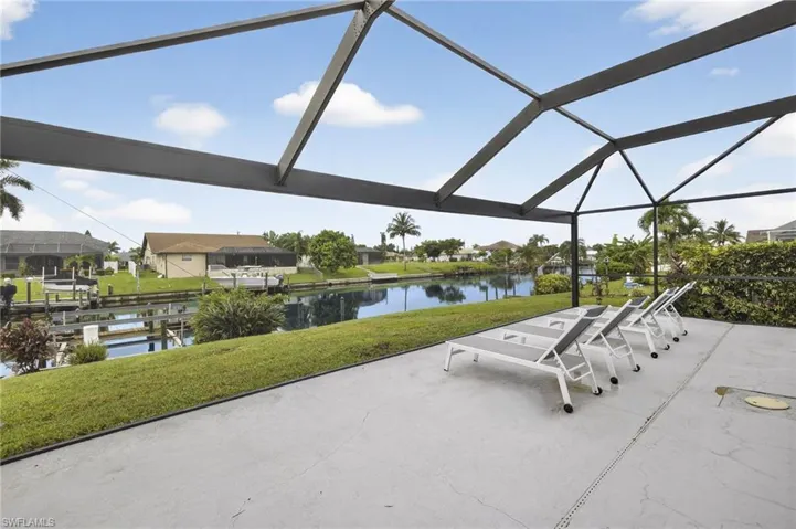 View of patio with a water view, a sunroom, glass enclosure, and a boat dock