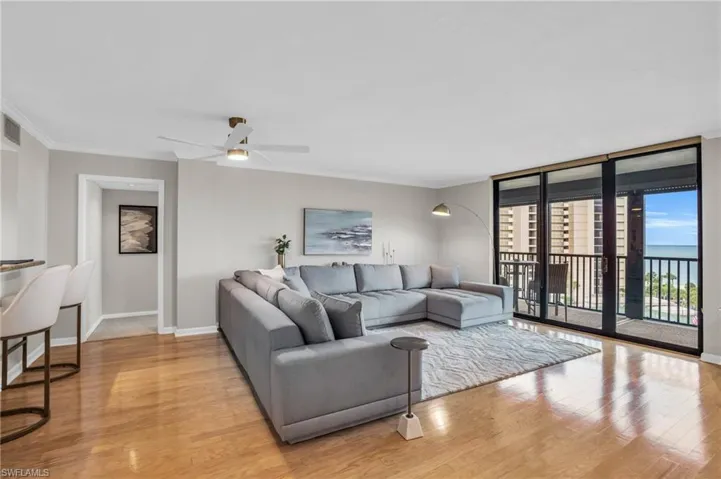 Living room featuring ceiling fan, light hardwood / wood-style floors, crown molding, and expansive windows