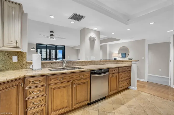 Kitchen featuring ceiling fan, dishwasher, light tile flooring, backsplash, and sink