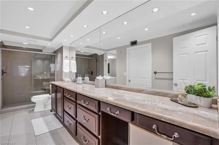 Bathroom with tile flooring, a raised ceiling, ornamental molding, toilet, and vanity