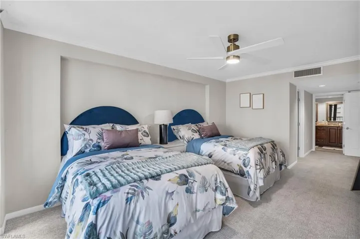 Bedroom with light carpet, ensuite bathroom, ornamental molding, and ceiling fan
