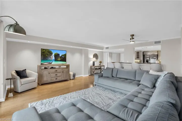 Living room with ornamental molding, ceiling fan, and light wood-type flooring