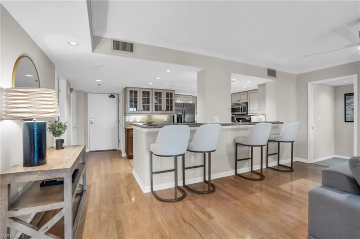 Kitchen with a kitchen breakfast bar, stainless steel appliances, light hardwood / wood-style floors, and kitchen peninsula