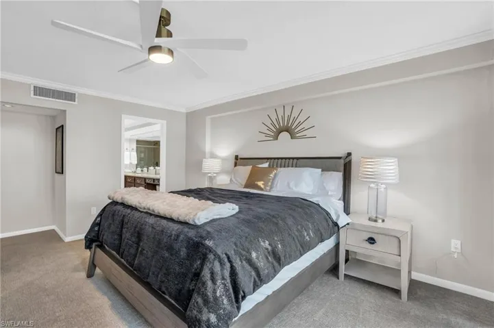 Carpeted bedroom featuring ensuite bathroom, ceiling fan, and crown molding