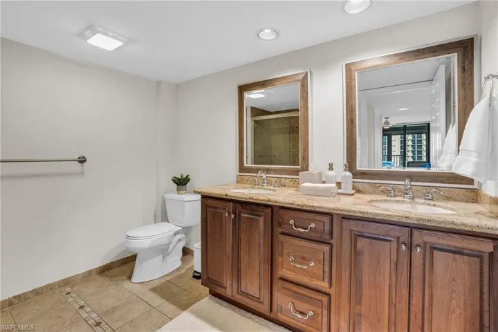 Bathroom featuring dual vanity, toilet, and tile floors