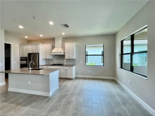 Kitchen with stainless steel appliances, white cabinets, backsplash, recessed lighting, and dark stone countertops