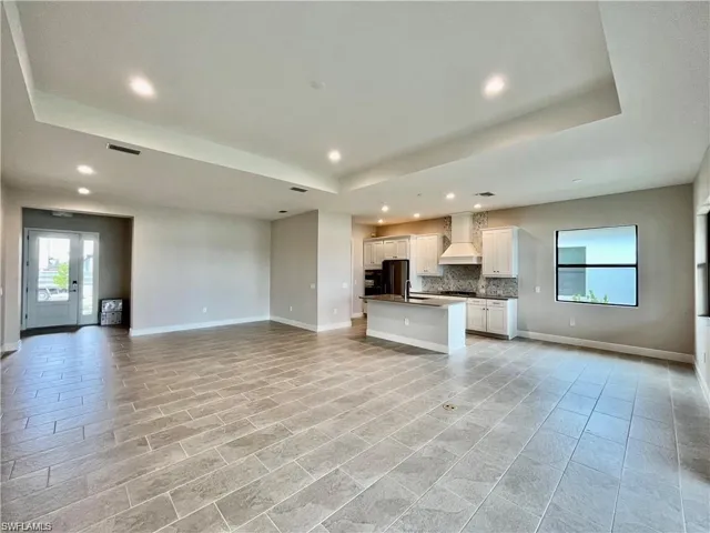 Unfurnished living room with healthy amount of natural light, a tray ceiling, and recessed lighting