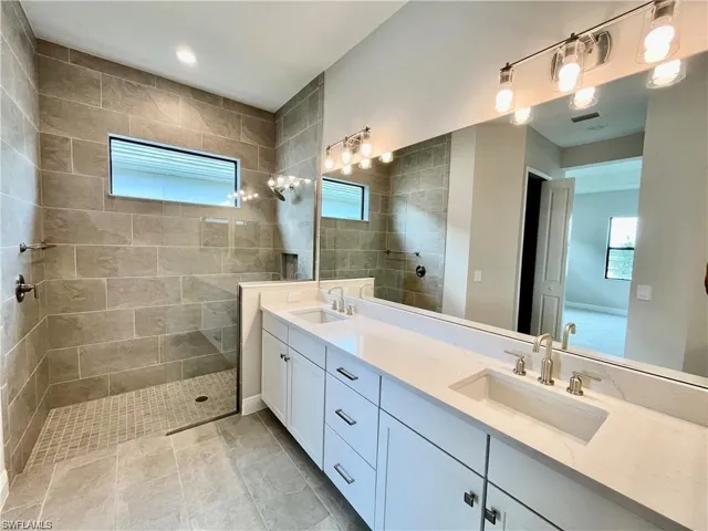 Full bathroom featuring double vanity, walk in shower, and recessed lighting