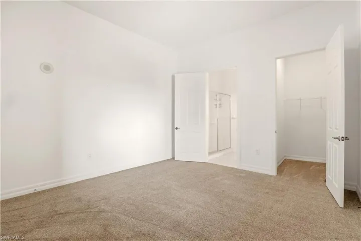 Unfurnished bedroom featuring a spacious closet, carpet, and connected bathroom