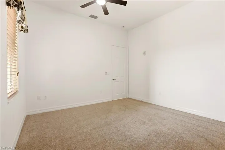 Carpeted empty room featuring baseboards and a ceiling fan