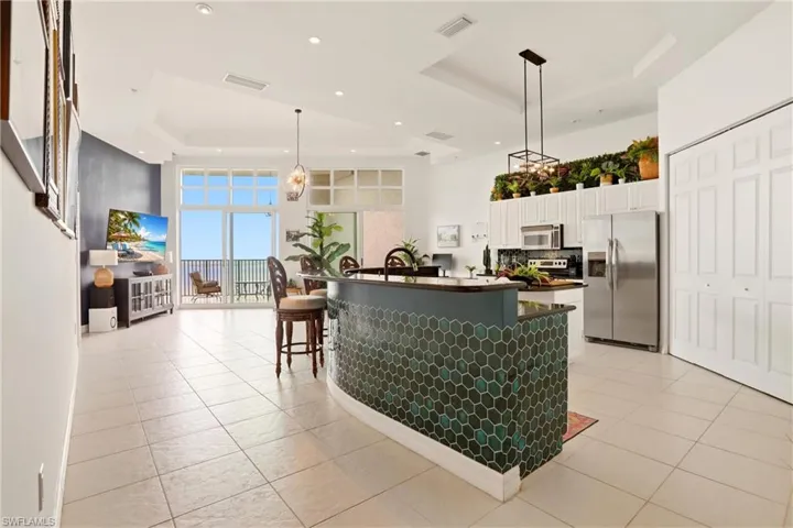 Kitchen with stainless steel appliances, a tray ceiling, white cabinets, a large island with sink, and a kitchen breakfast bar