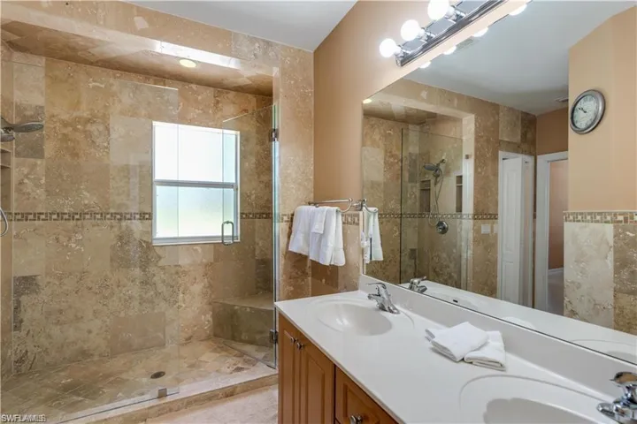 Full bathroom featuring double vanity and a stall shower