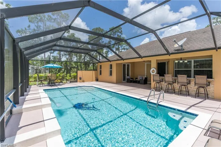 Swimming pool featuring a patio area, a sunroom, glass enclosure, and outdoor dining area