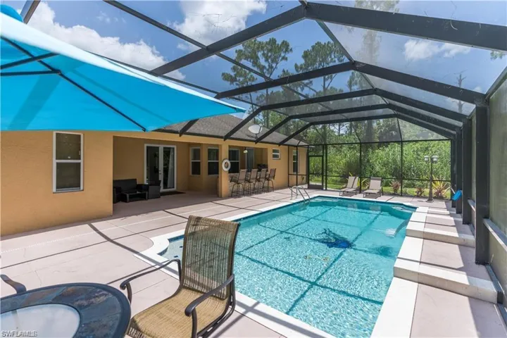 Swimming pool with a patio area, glass enclosure, a sunroom, and french doors
