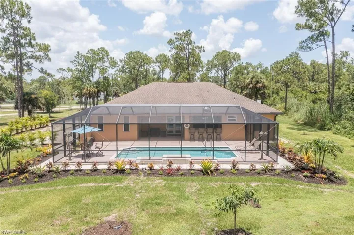Swimming pool featuring glass enclosure, a sunroom, and a yard