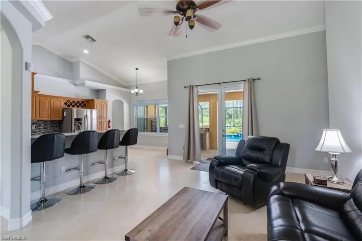 Living room with arched walkways, crown molding, ceiling fan, high vaulted ceiling, and recessed lighting