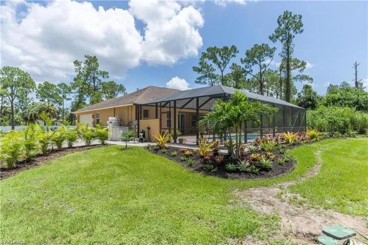 Rear view of property featuring glass enclosure, a sunroom, a yard, and an outdoor pool