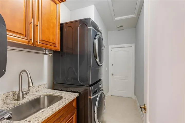 Laundry room with stacked washer / dryer and cabinet space