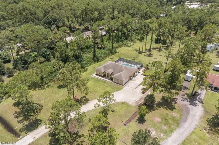 Aerial view of property and surrounding area featuring a forest