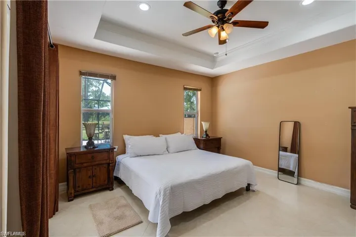 Bedroom featuring a tray ceiling, a ceiling fan, and recessed lighting
