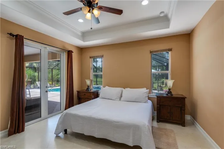 Bedroom with a tray ceiling, french doors, access to outside, a ceiling fan, and recessed lighting