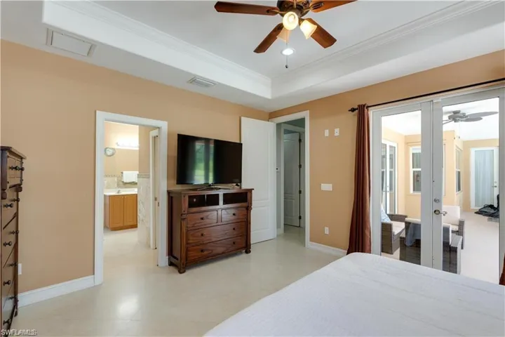 Bedroom with crown molding, french doors, ceiling fan, a tray ceiling, and access to exterior