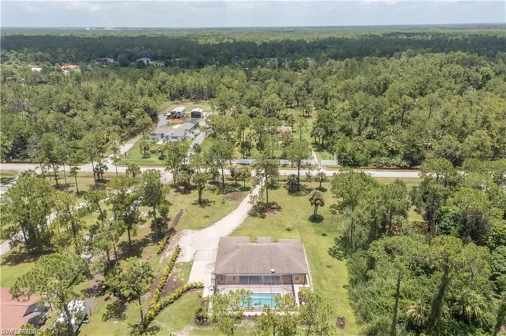 Aerial overview of property's location featuring a heavily wooded area and a pool area
