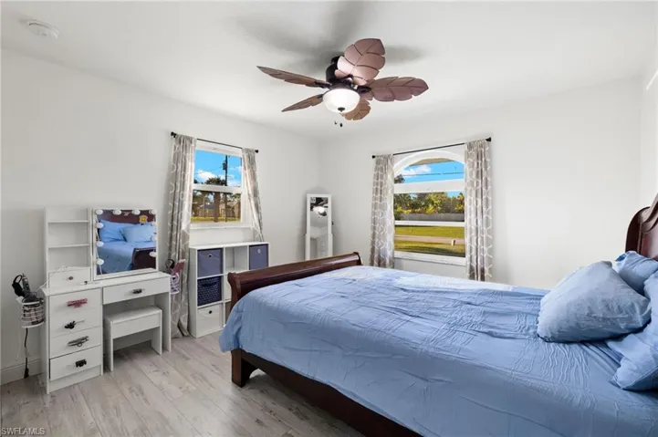 Bedroom with ceiling fan, multiple windows, and light hardwood / wood-style floors