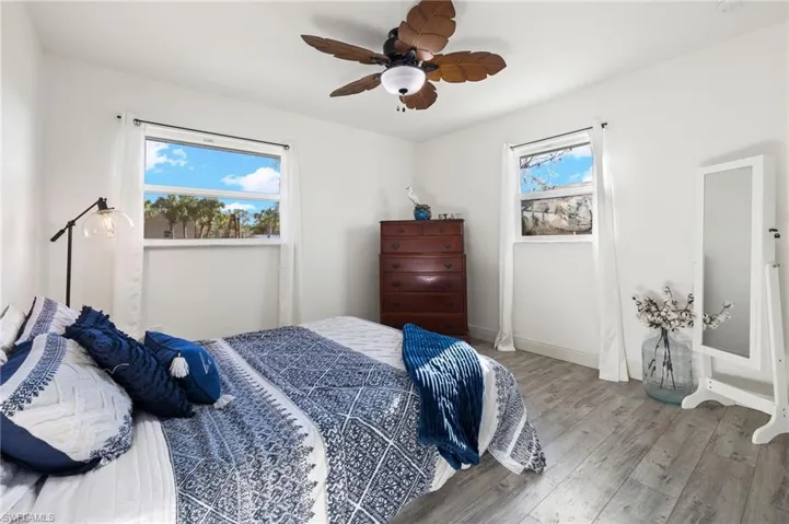 Bedroom with multiple windows, hardwood / wood-style floors, and ceiling fan