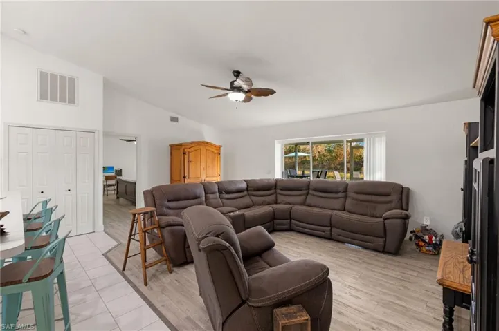 Living room with lofted ceiling, light wood-type flooring, and ceiling fan