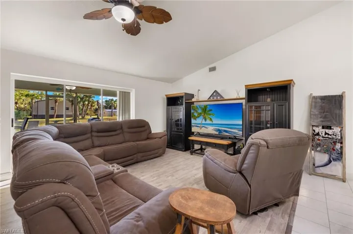 Living room featuring high vaulted ceiling, light wood-type flooring, and ceiling fan