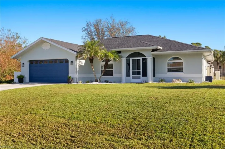 Ranch-style house featuring a front yard and a garage