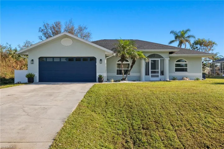 Ranch-style house with a garage and a front lawn
