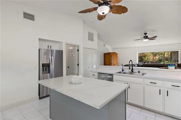 Kitchen with kitchen peninsula, appliances with stainless steel finishes, white cabinetry, sink, and a center island