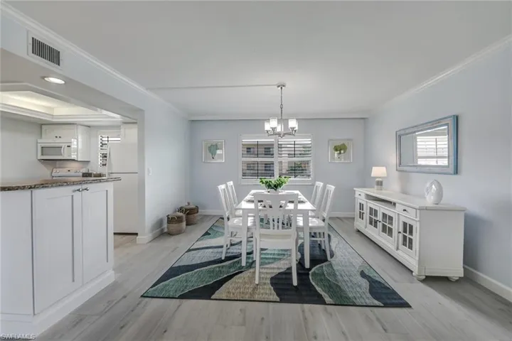 Dining area featuring a chandelier, crown molding, and light wood finished floors