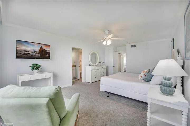 Carpeted bedroom featuring crown molding, ceiling fan, and ensuite bathroom
