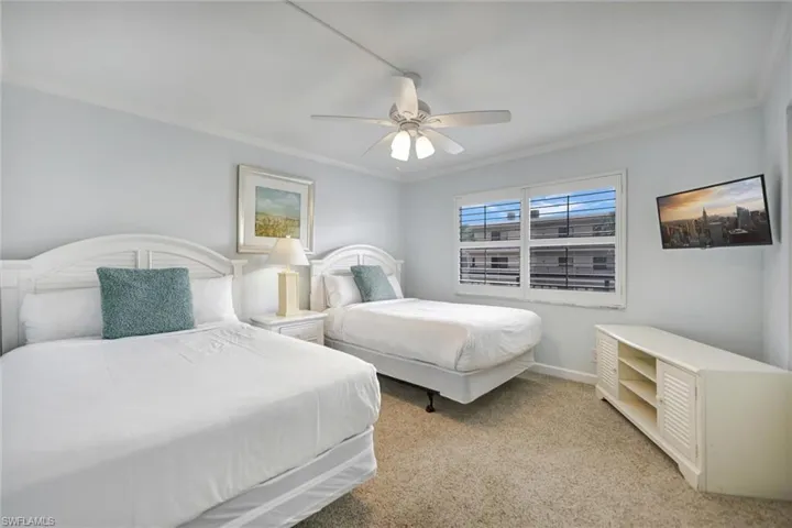 Carpeted bedroom with crown molding and a ceiling fan