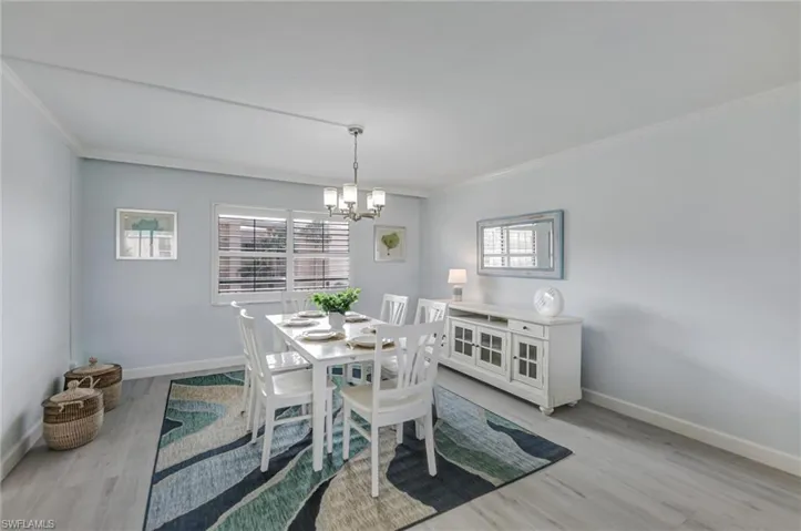 Dining room with ornamental molding, a chandelier, and light wood-type flooring