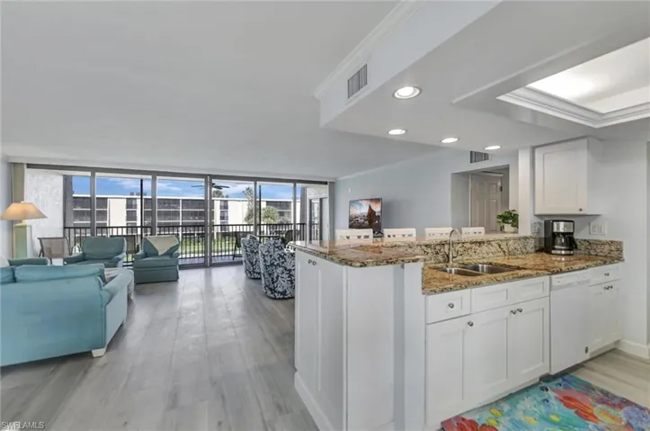 Kitchen featuring ornamental molding, white cabinets, expansive windows, dark stone countertops, and open floor plan