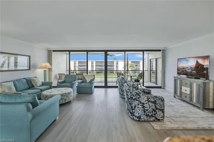 Living area with ornamental molding, a wall of windows, and wood finished floors