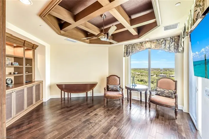 Flexible bonus room (den/office)  with wood flooring, built-in cabinetry, and custom ceiling detail.