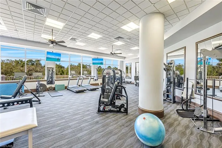 Fully equipped fitness center with large windows, ample natural light, and a variety of exercise equipment.