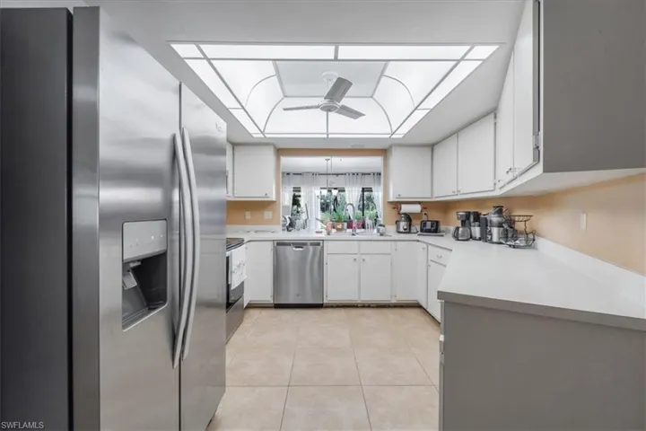Kitchen featuring stainless steel appliances, light countertops, white cabinetry, and light tile patterned floors
