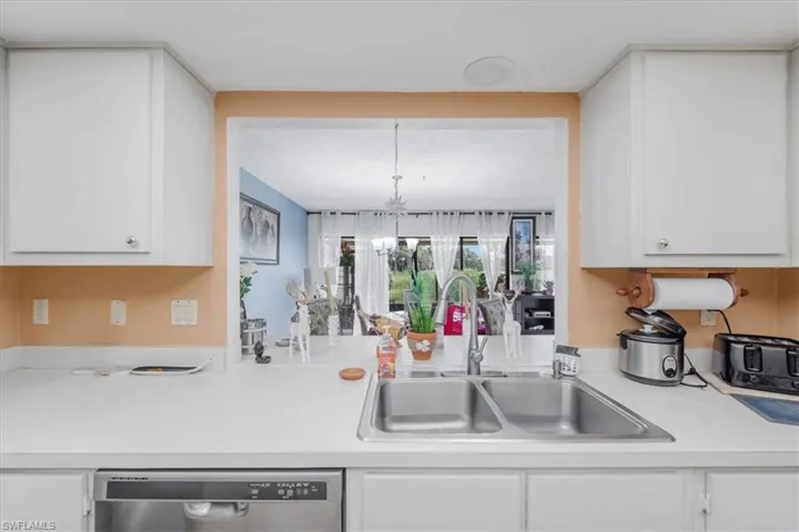 Kitchen with white cabinets, light countertops, and stainless steel dishwasher