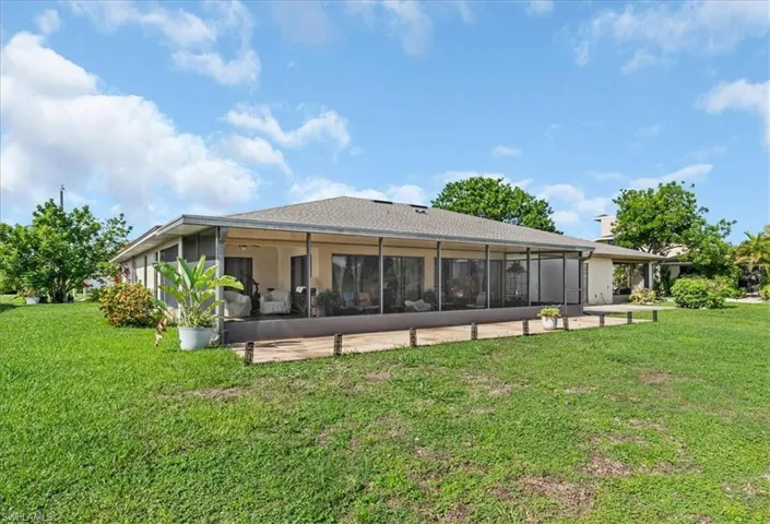 Rear view of house with a yard, stucco siding, and a sunroom