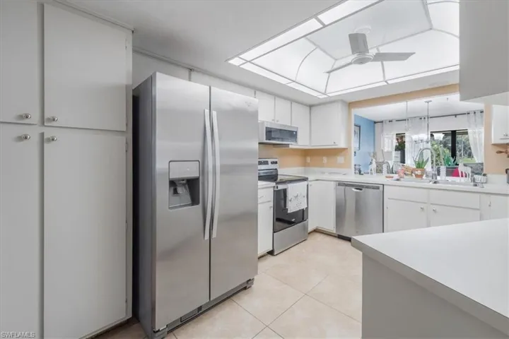 Kitchen with stainless steel appliances, light countertops, white cabinetry, and ceiling fan